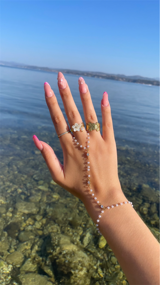 Chaine de main doree portee look moderne avec perles blanches nacres et zirconium