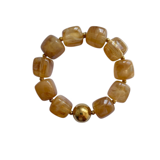 Bracelet en résine beige jaune effet marbré avec finitions en acier inoxydable doré, ajustable et résistant à l’eau, bijou léger pour femme.